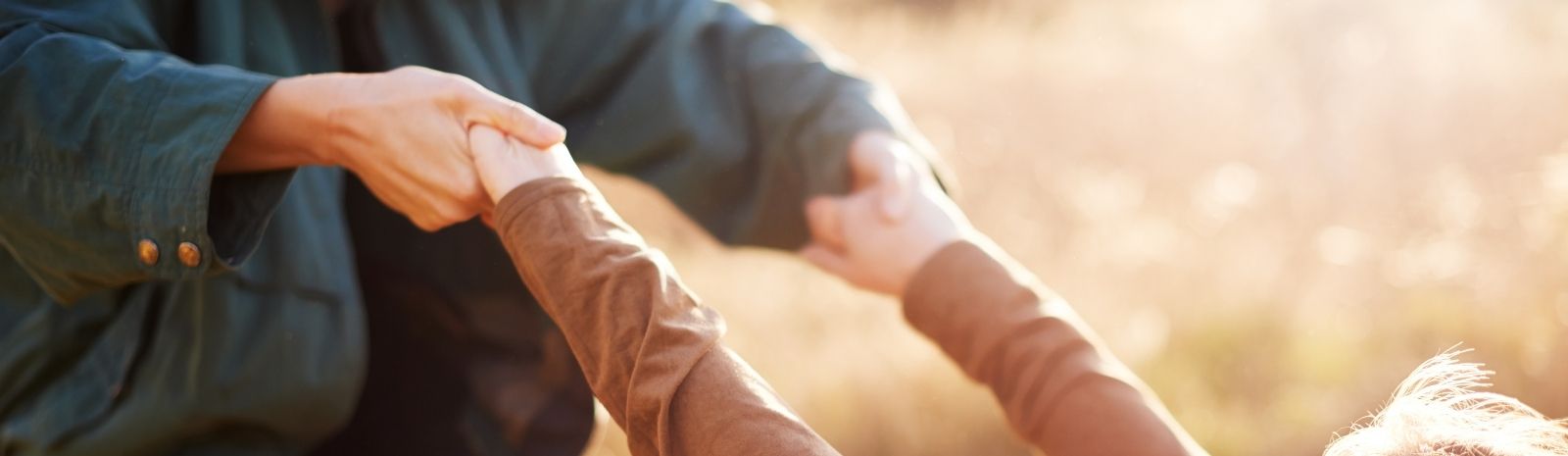 Cropped shot of two people holding hands while hiking outdoors