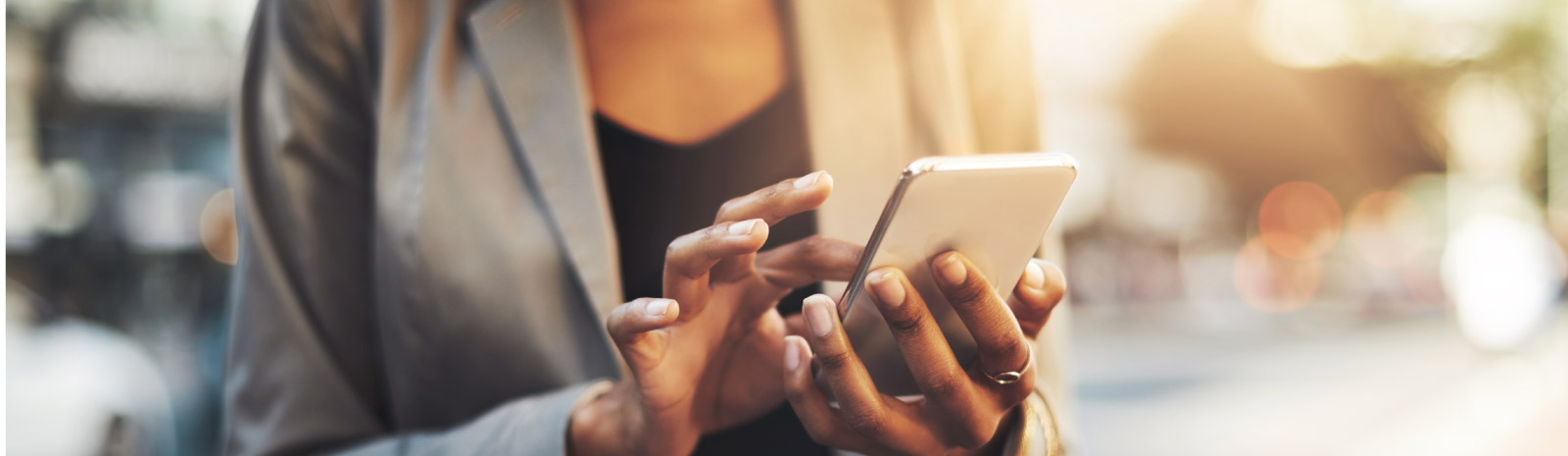 Woman taps her phone screen while outdoors