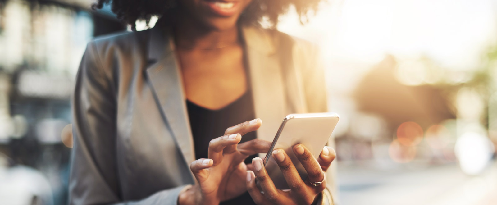 Woman taps her phone screen while outdoors