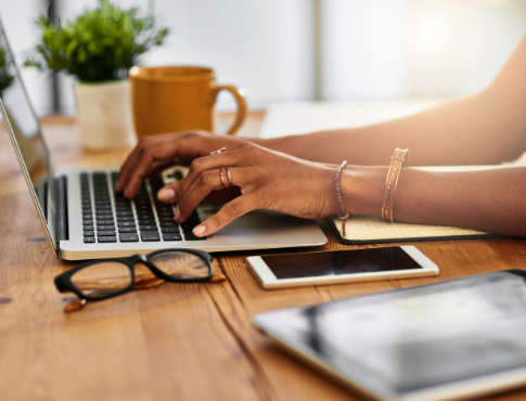 Person typing on laptop with plant and coffee in background