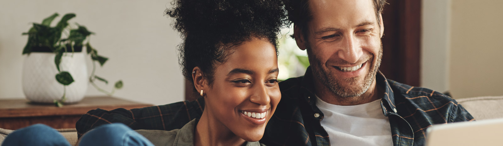 Man and woman look at a tablet screen together while sitting on a couch